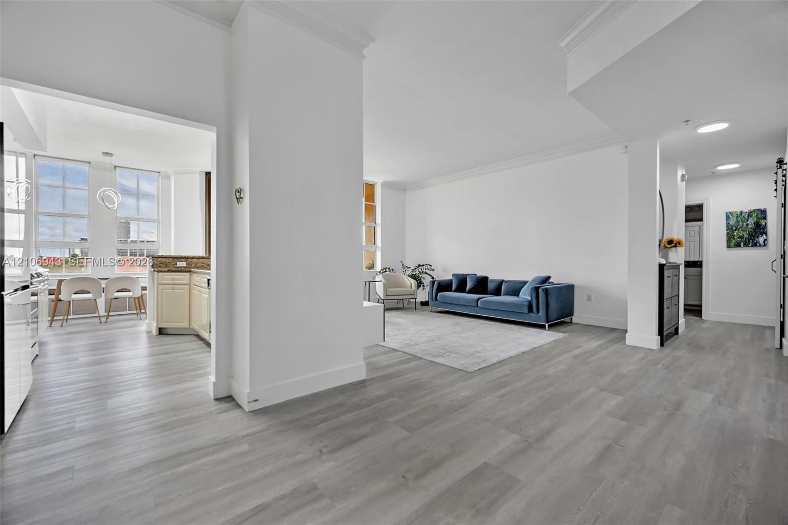 Open-concept interior featuring wood-finish flooring, crown molding, recessed lighting, and multi-pane windows