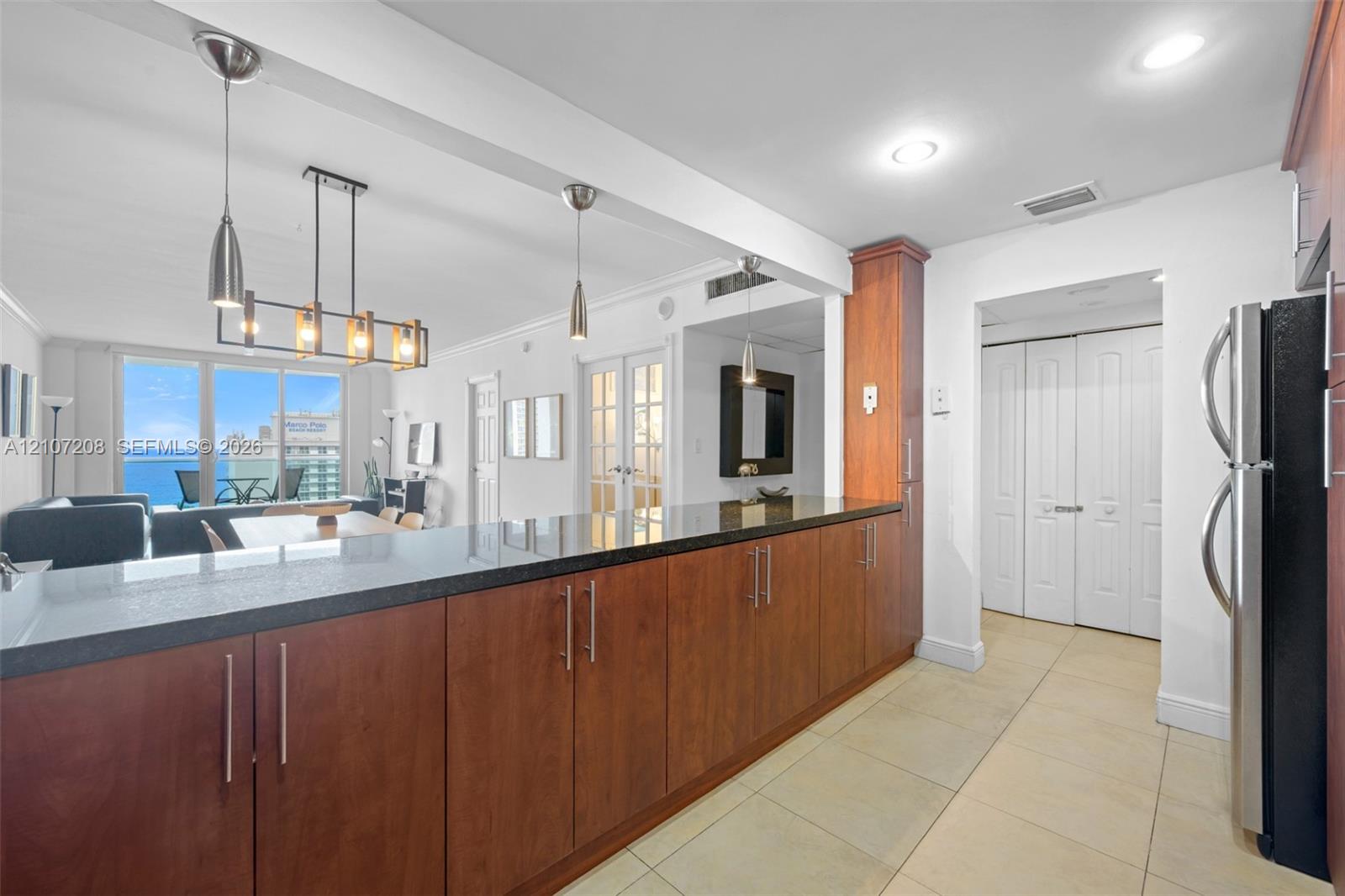 Kitchen featuring wood cabinetry, dark stone-finish countertops, recessed lighting, tile flooring, and a multi-light pendant fixture