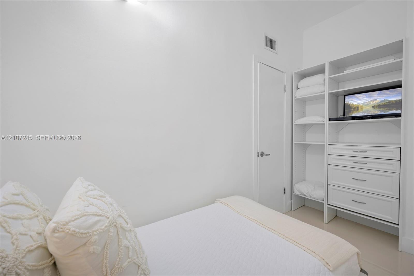 Built-in white storage cabinetry featuring open shelving and integrated drawers
