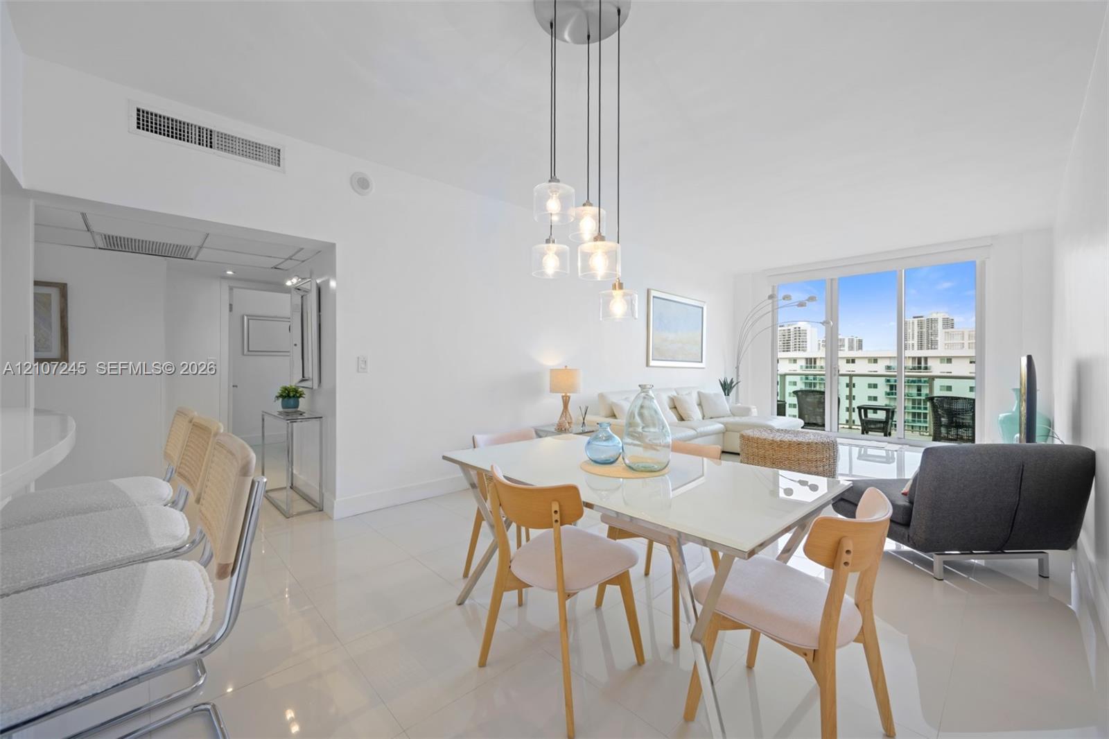 Open-concept living space featuring high-gloss tile flooring, multi-pendant glass lighting, built-in recessed ceiling lighting, and floor-to-ceiling glass sliding doors