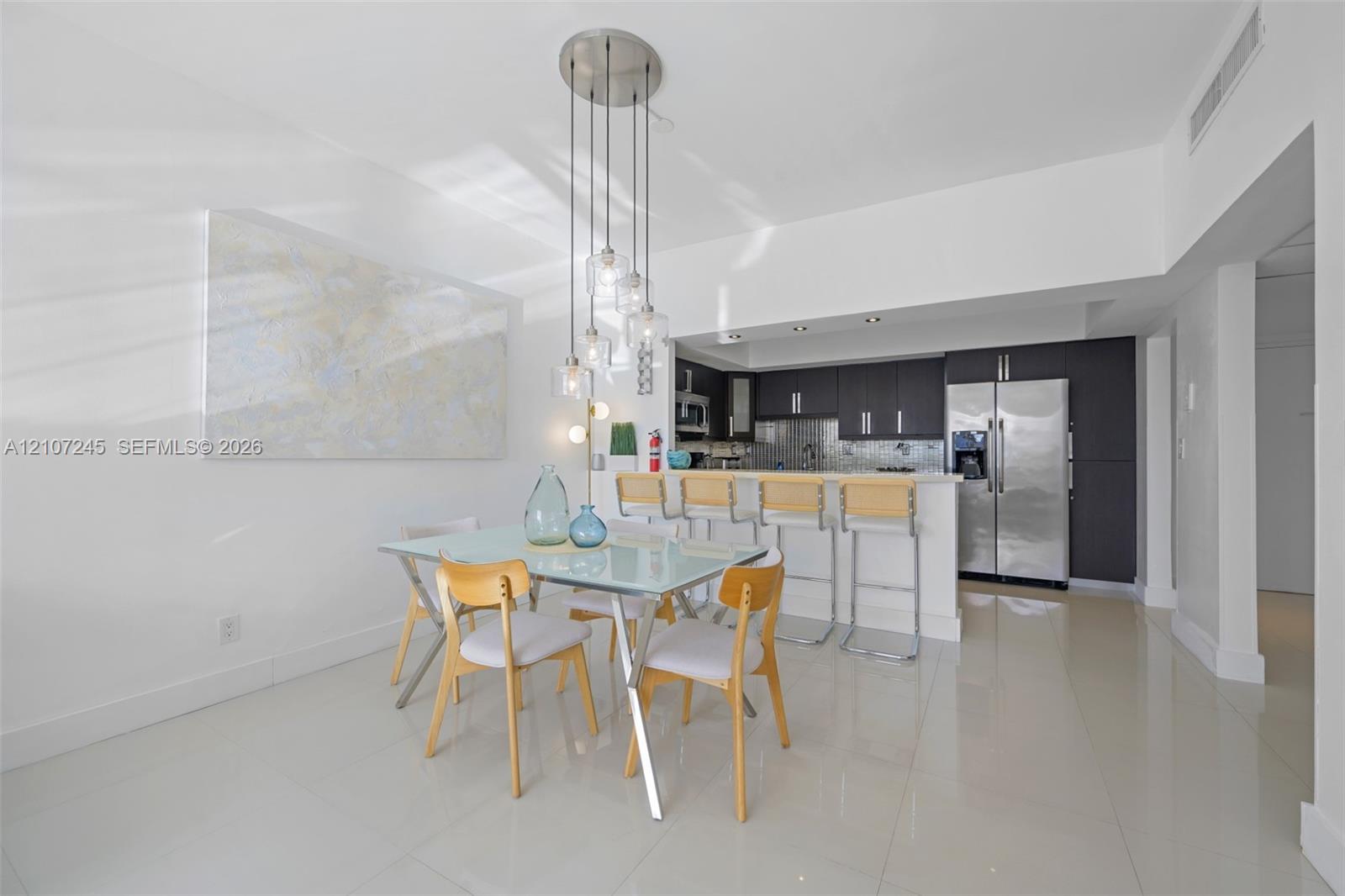 Kitchen featuring dark cabinetry, stainless steel appliances, breakfast bar, and multi-light pendant fixture over tile flooring