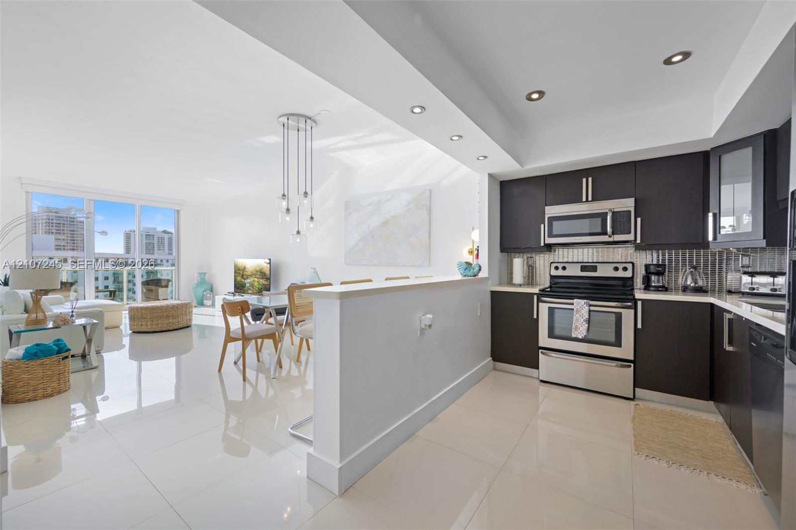 Kitchen featuring dark cabinetry, stainless steel appliances, recessed lighting, and large-format tile flooring