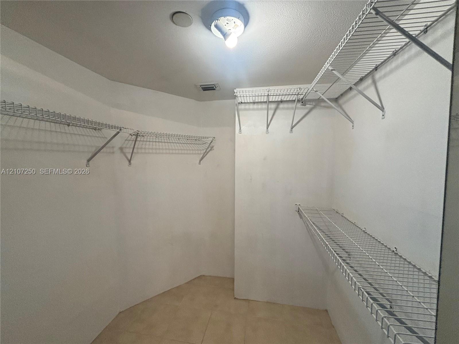 Walk-in closet featuring ceramic tile flooring, tiered wire shelving, and a ceiling-mounted light fixture