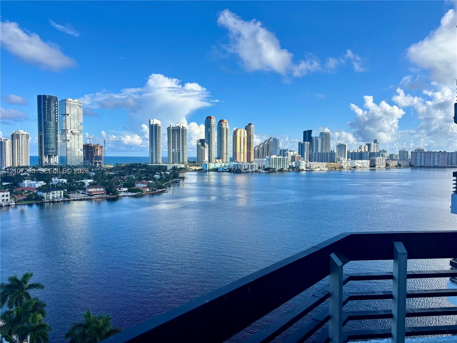Private balcony with dark metal railings overlooking the water and metropolitan skyline