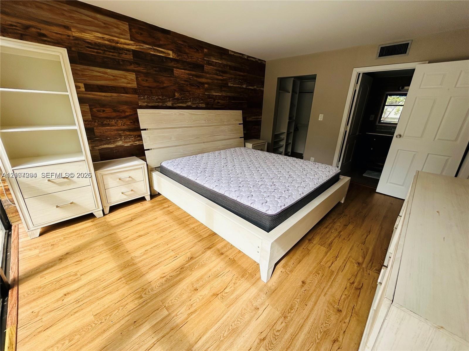 Accent wall featuring horizontal wood paneling, wood-finish flooring, and built-in shelving unit