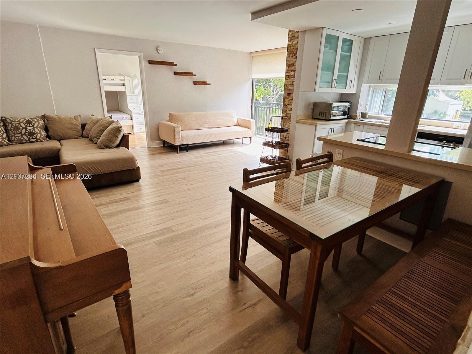Open-concept interior featuring light wood-finish flooring, white cabinetry, quartz-surface countertops, and decorative stone accent wall detailing
