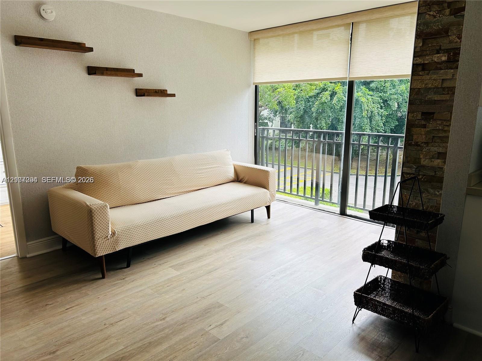 Living area featuring wood-finish flooring, floor-to-ceiling sliding glass doors, built-in wooden wall shelves, and a floor-to-ceiling stacked stone accent pillar