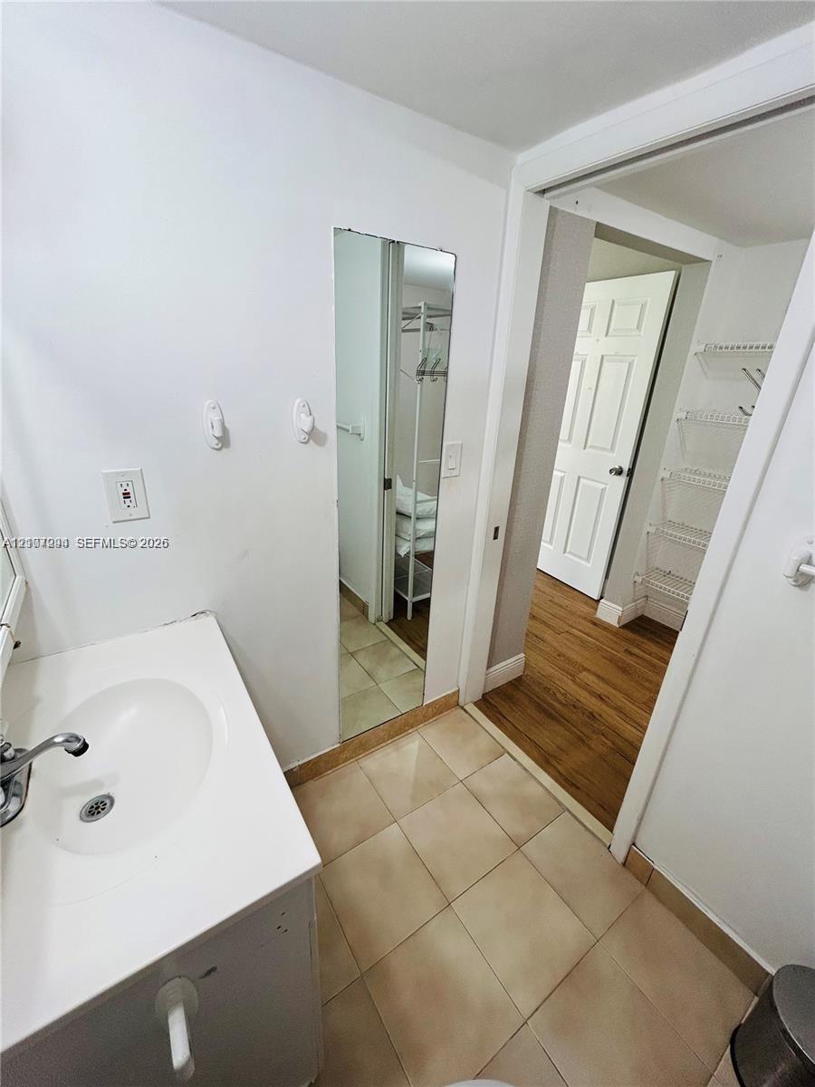 Vanity featuring a white integrated sink, ceramic tile flooring, and flush-mounted wall mirror
