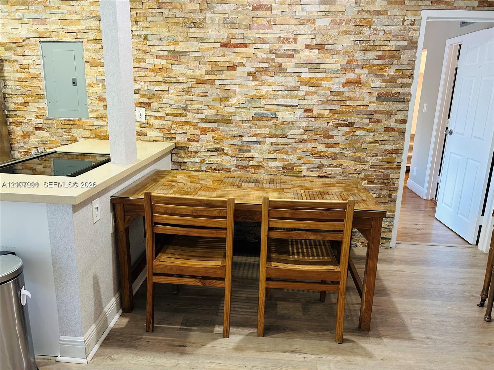 Stacked stone accent wall with wood-finish flooring and a kitchen counter featuring a solid surface countertop