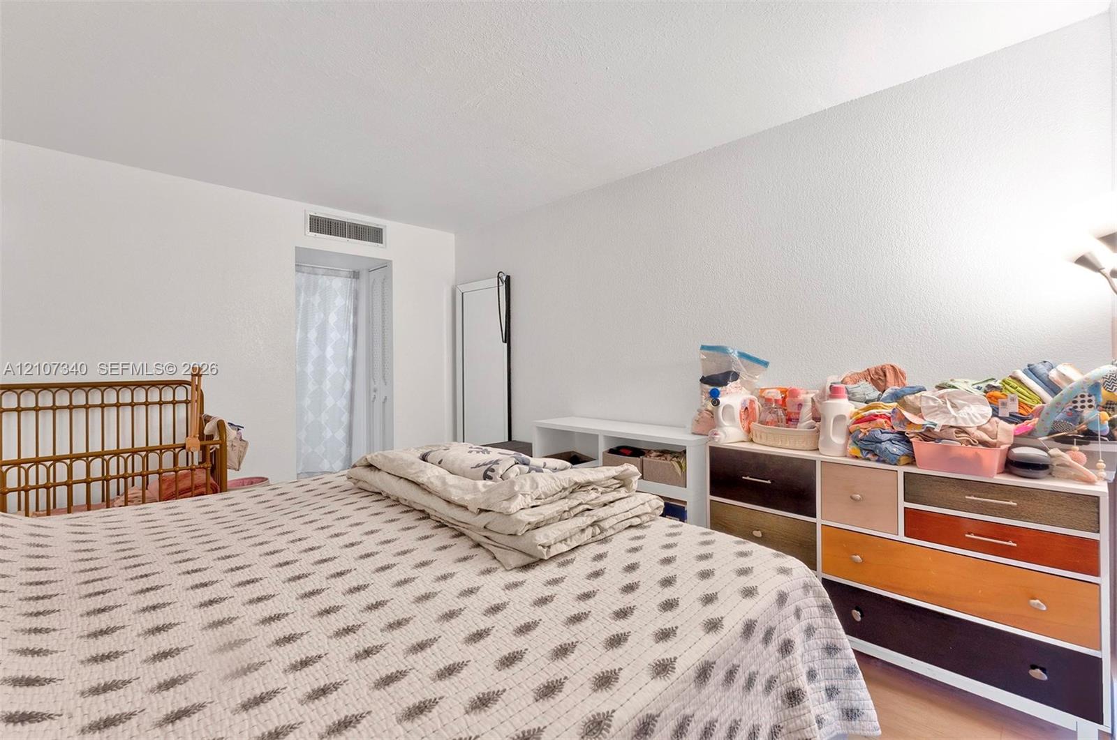Room interior featuring white walls, wood-finish flooring, and a doorway leading to a private area