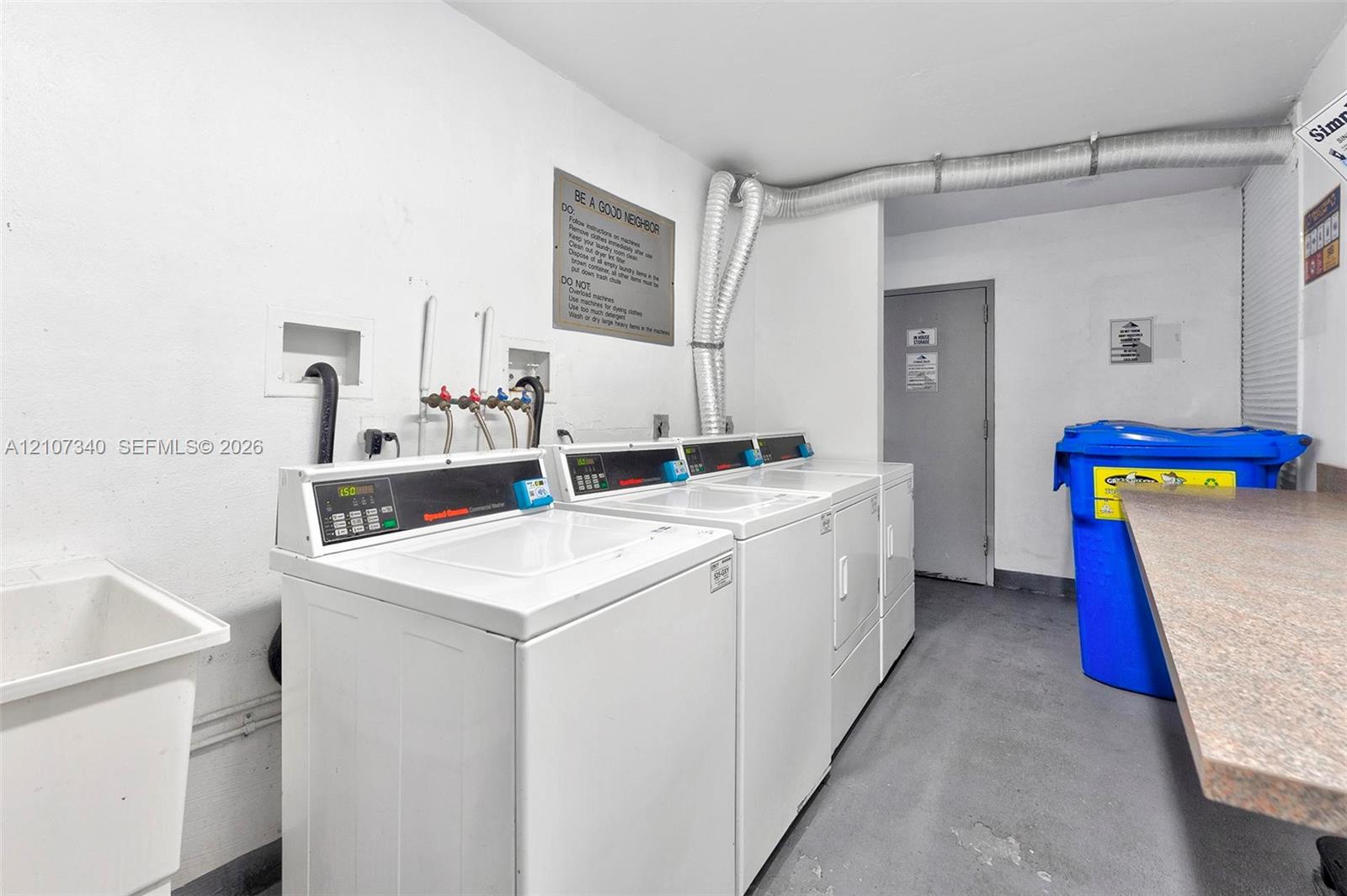 Utility area featuring a deep basin utility sink, multiple laundry appliances, and a laminate-surface folding counter
