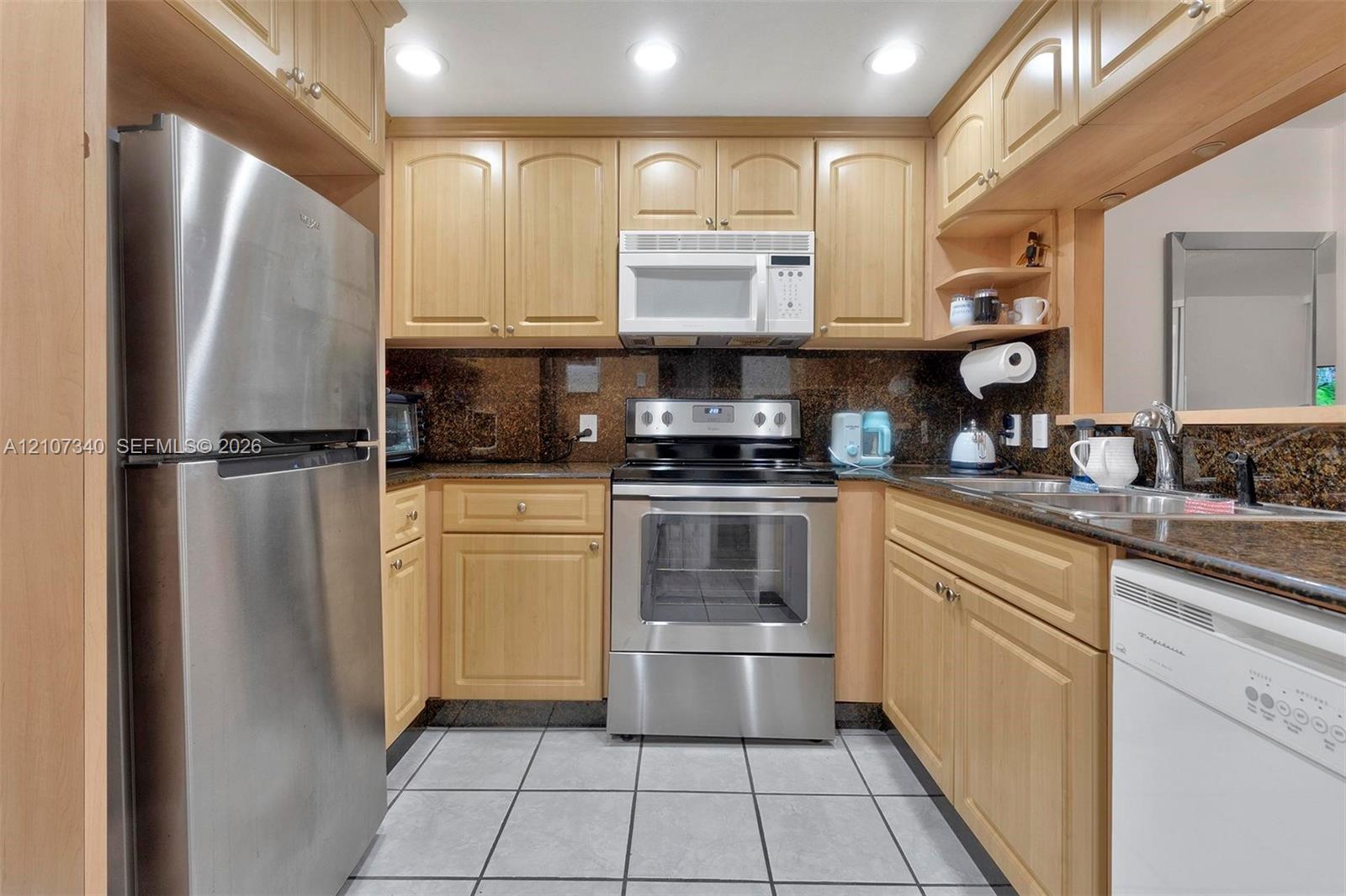 Kitchen featuring light-finish wood cabinetry, stone countertops, stainless steel appliances, recessed ceiling lighting, and tiled flooring