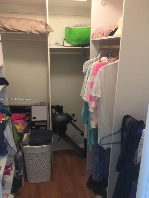 Custom closet system featuring white laminate shelving, vertical partitions, and integrated wooden garment rods with wood-finish flooring