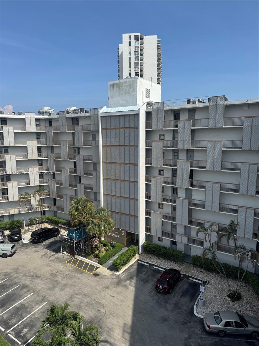 Multi-story residential complex featuring geometric facade detailing, exterior-facing balconies, and dedicated surface parking