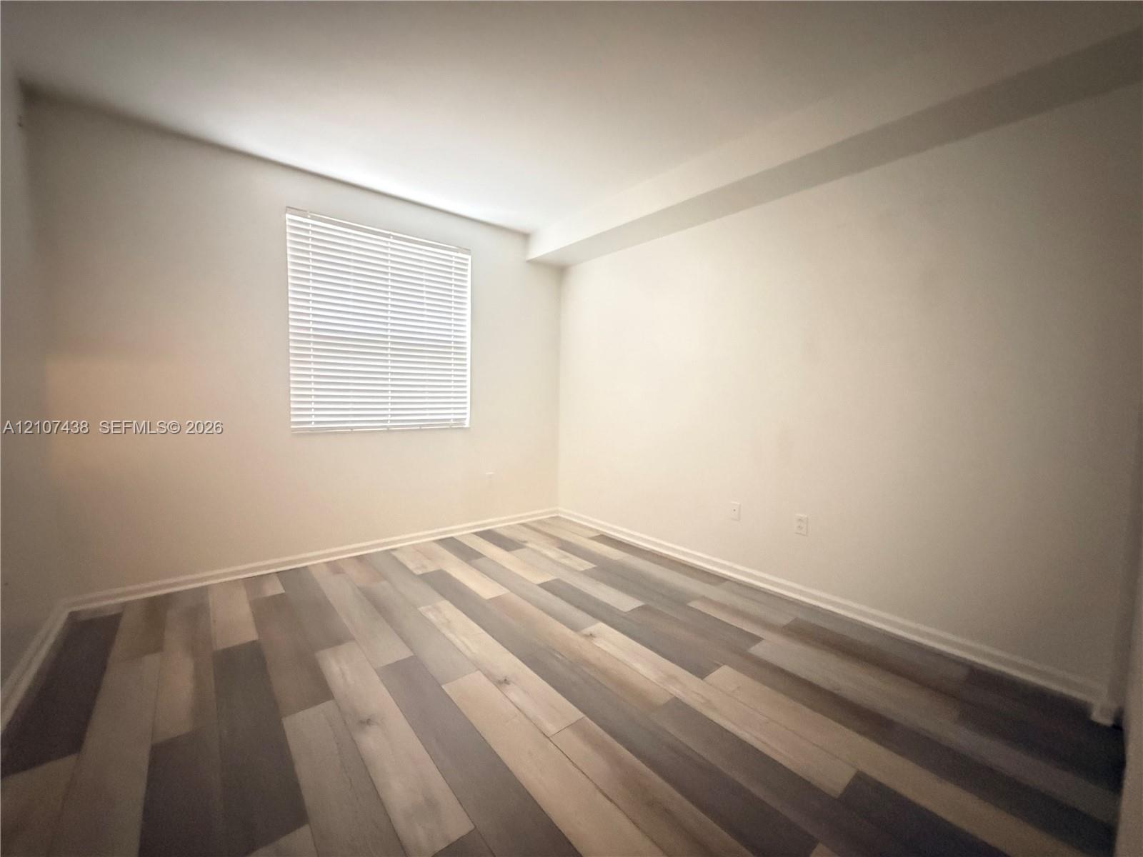 Interior space featuring neutral wall paint and multi-toned wood-finish flooring
