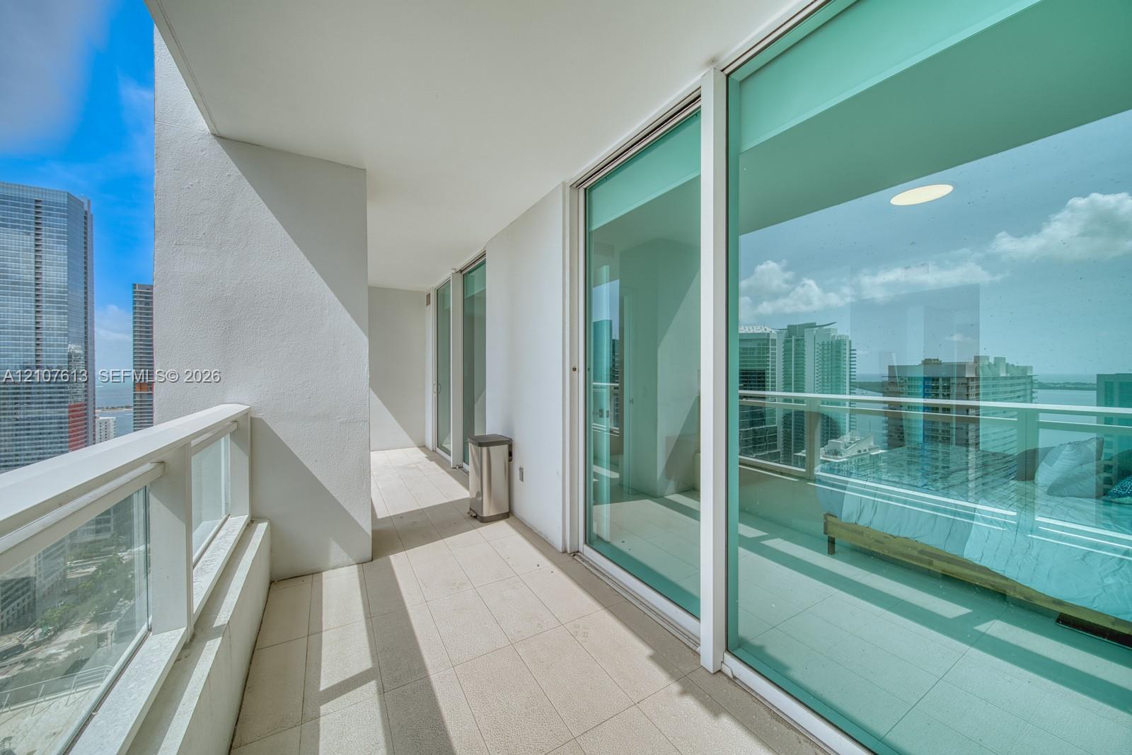 Covered balcony featuring tile flooring and a glass panel railing