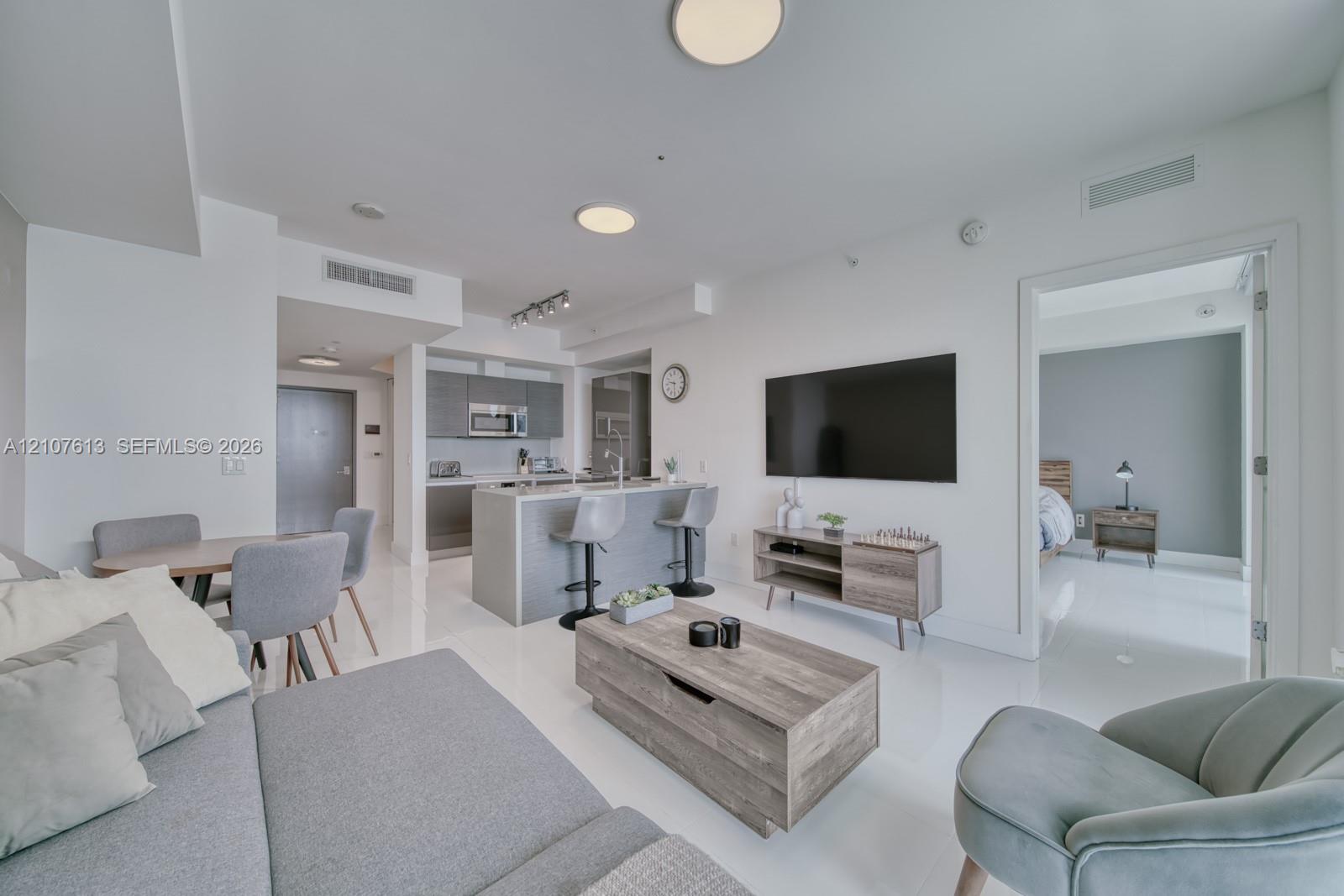Open-concept interior featuring high-gloss flooring, recessed ceiling lighting, and a kitchen island with stone-finish countertops and integrated cabinetry
