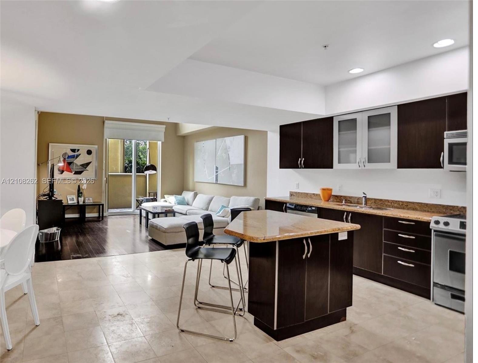 Kitchen featuring dark-toned cabinetry, stone countertops, a central island, and recessed lighting