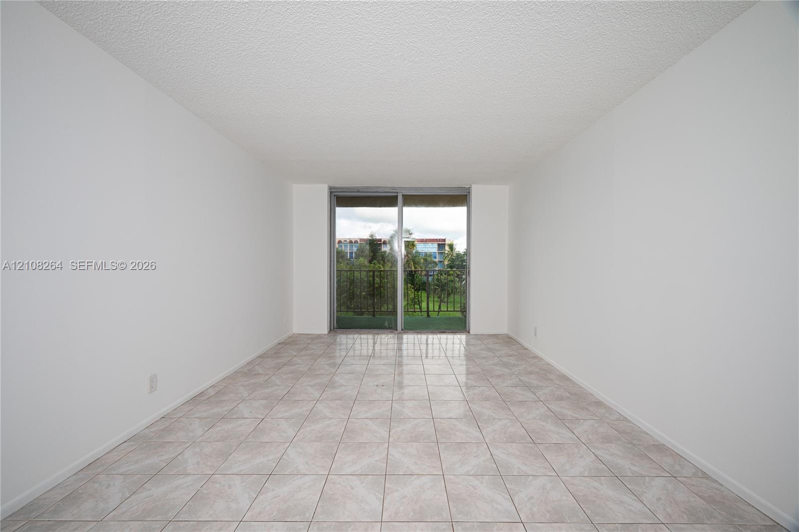 Neutral-toned floor tiles and sliding glass doors leading to a private balcony