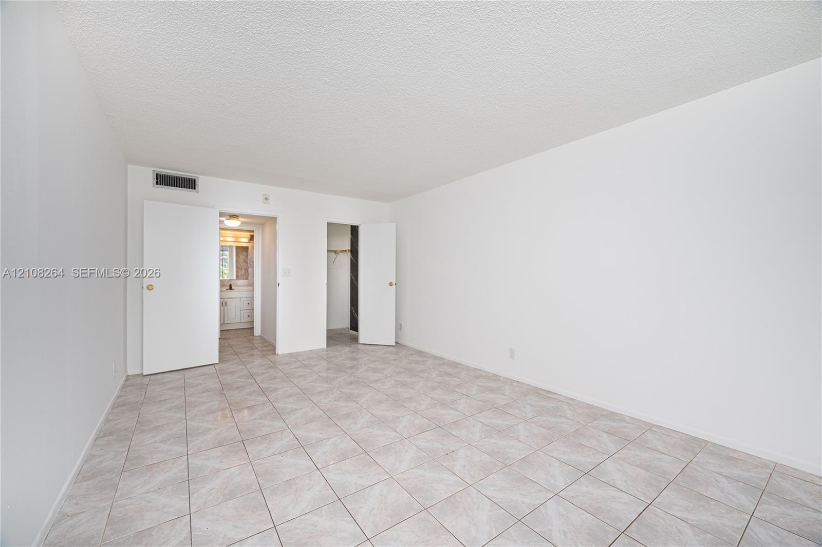 Neutral-toned tile flooring, white interior walls, and dual swinging doors opening to a secondary room