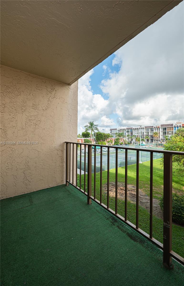 Covered balcony featuring textured stucco walls and metal railings