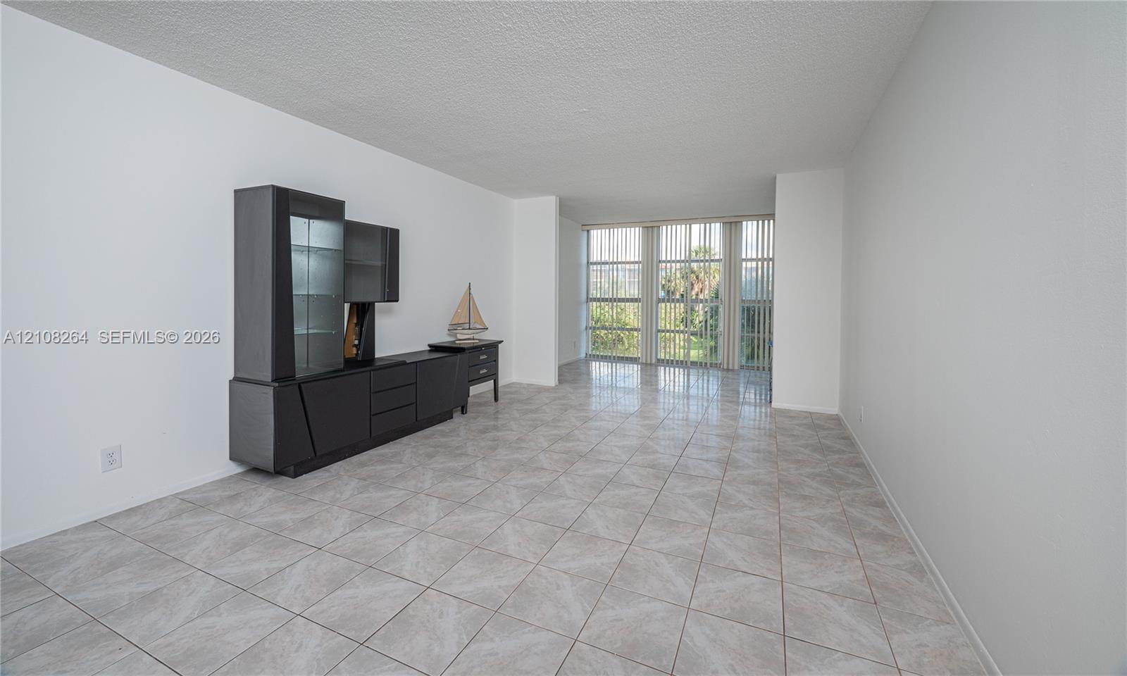 Neutral ceramic tile flooring, expansive floor-to-ceiling windows, and vertical blinds