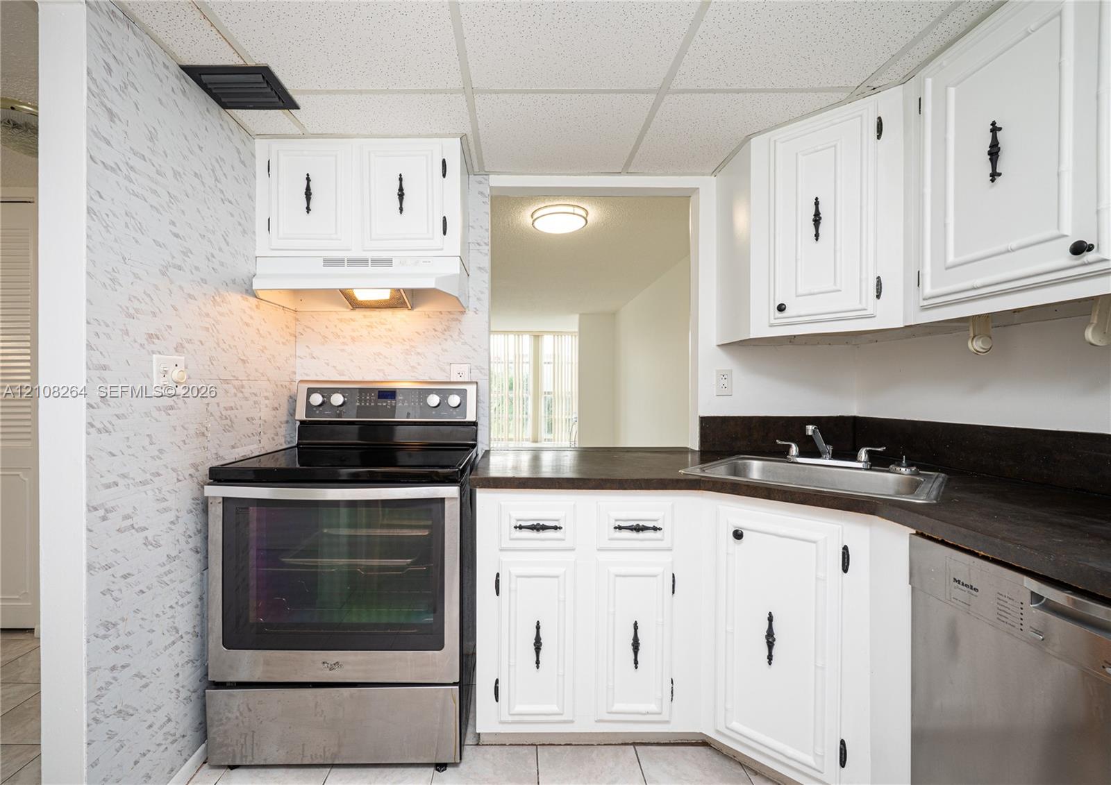 Kitchen featuring white cabinetry with dark hardware, dark countertops, a stainless steel range, and a stainless steel dishwasher