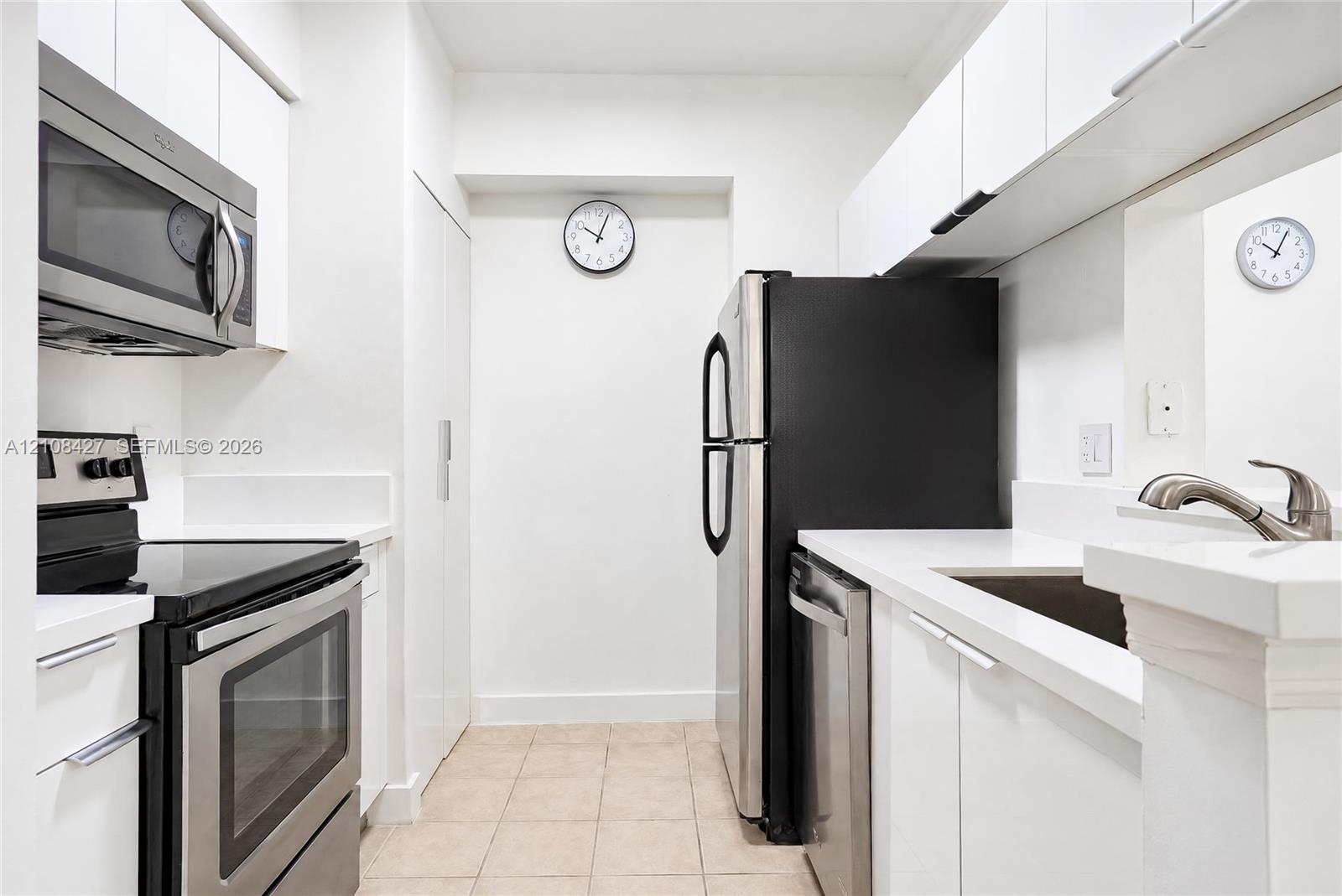 Kitchen featuring white cabinetry, solid-surface countertops, tile flooring, and a stainless steel appliance suite