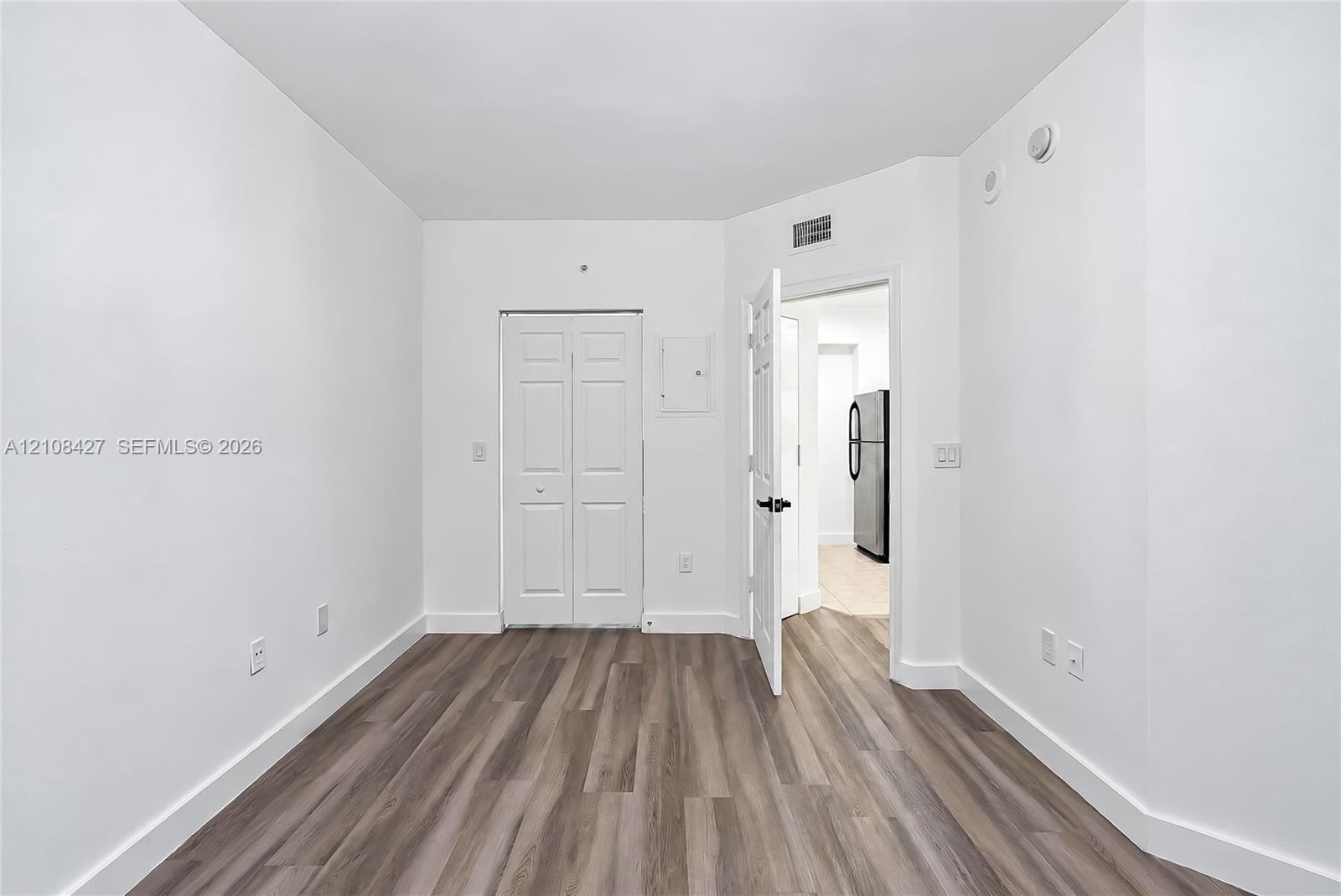 Interior space featuring wood-finish flooring, white walls, and a built-in closet with double bifold doors