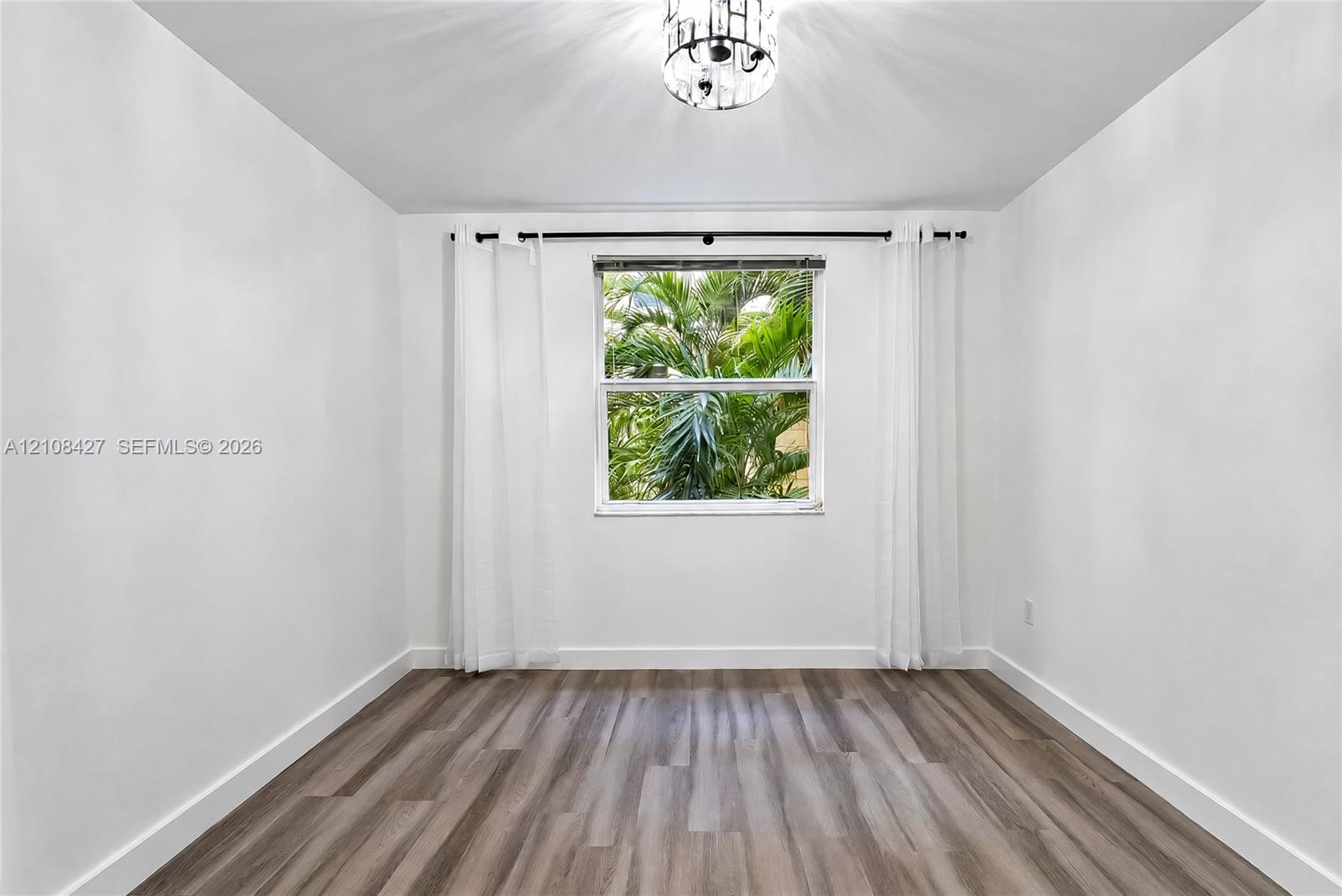 Interior room featuring wood-finish flooring, a single window, and a drum-style ceiling light fixture