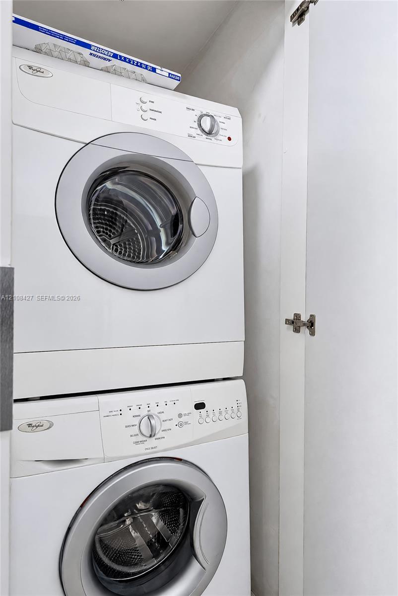 Stacked front-loading washer and dryer unit enclosed within a built-in cabinetry closet