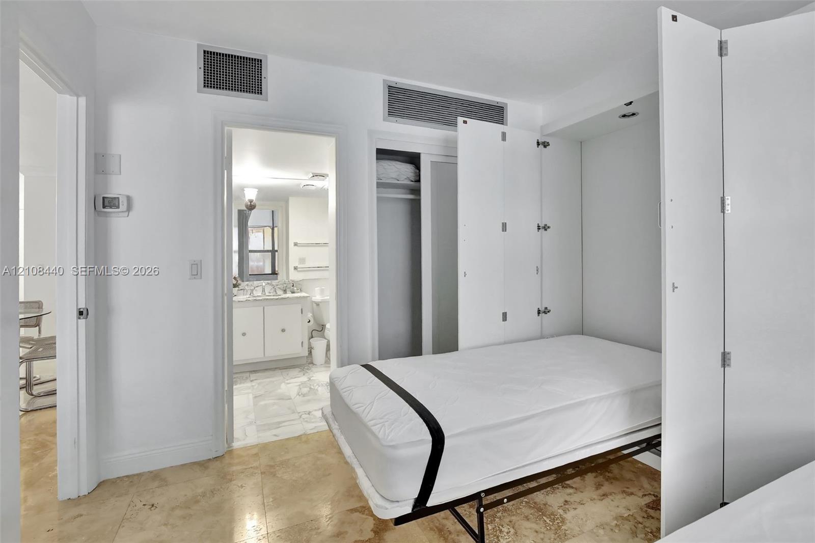 Built-in white storage cabinetry, polished stone flooring, and recessed ceiling lighting