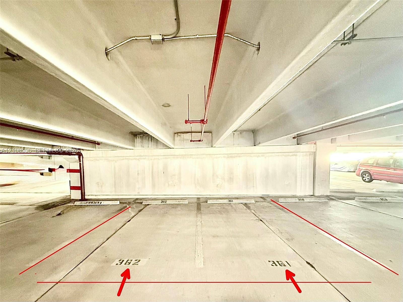 Covered parking structure featuring concrete flooring, marked stall numbers 361 and 362, and overhead fire suppression infrastructure