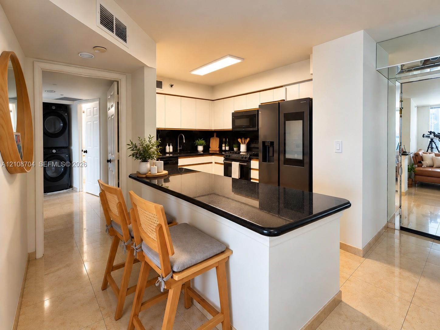 Kitchen featuring white cabinetry, black countertop, matching black appliances, and neutral tile flooring