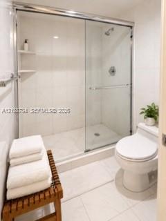 Walk-in shower featuring sliding glass doors, chrome hardware, integrated tile shelving, and tile flooring