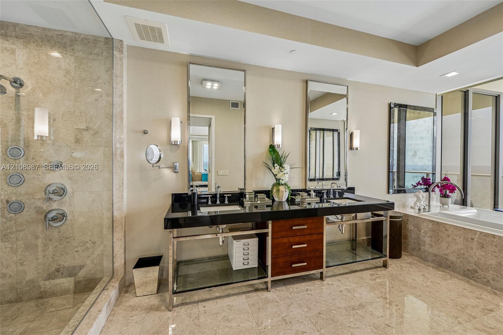 Dual-vanity metal console with a dark stone countertop, integrated glass shelving, and wood-finish cabinetry