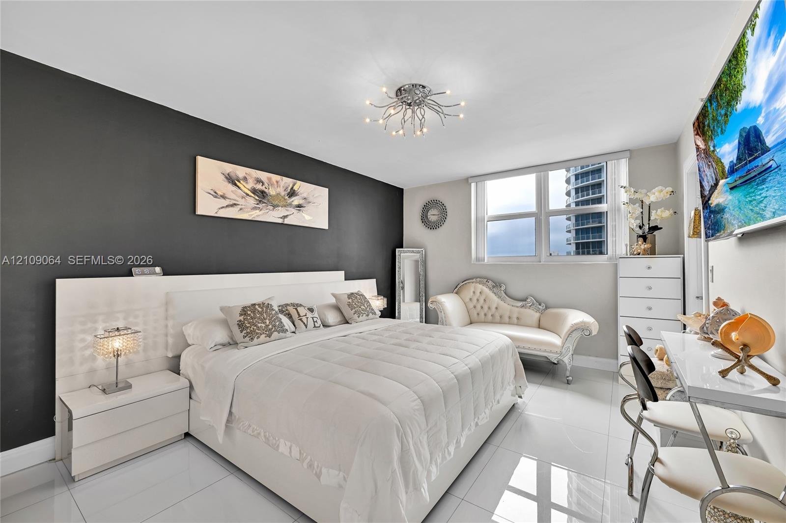 Spacious room featuring high-gloss tile flooring, an accent wall, multi-pane window, and a decorative ceiling-mounted light fixture