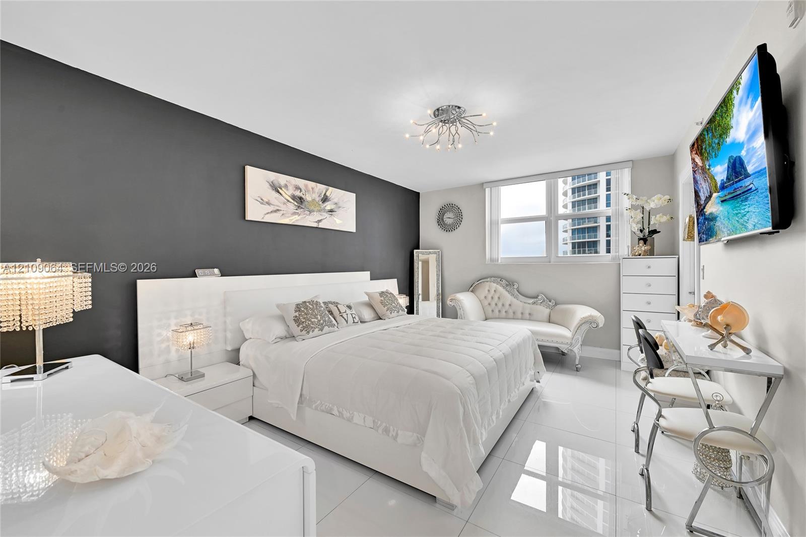Sleeping area featuring high-gloss white built-in cabinetry, polished tile flooring, a charcoal accent wall, and a contemporary multi-arm chrome chandelier