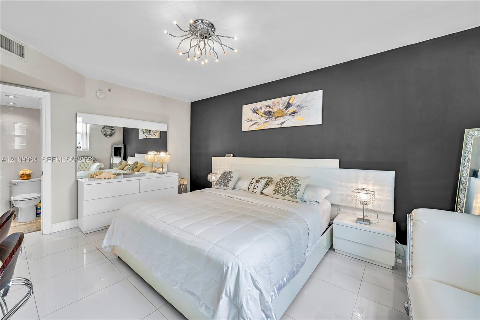Accent wall with a neutral finish, polished tile flooring, and multi-arm brass flush-mount light fixture