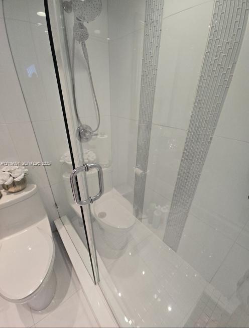 Glass-enclosed shower featuring large-format wall tile, decorative vertical mosaic accent inlay, and adjustable chrome shower head