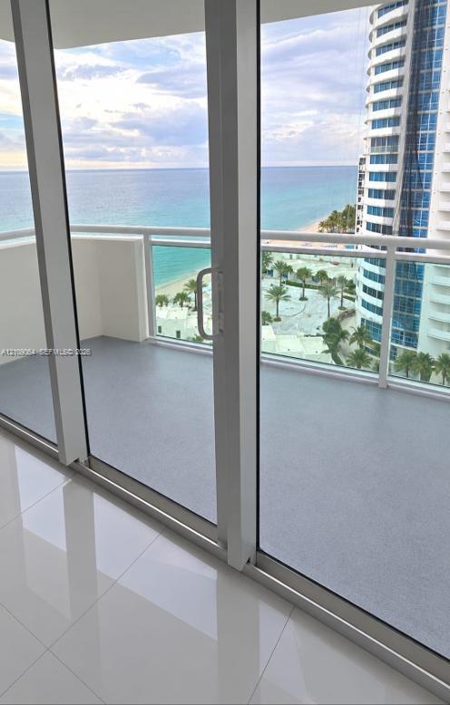 Floor-to-ceiling windows with white frames, showcasing coastal scenery including an expansive ocean and sand shoreline