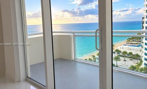 Aerial perspective of coastal property featuring an expansive swimming pool with hardscaped surround, multiple cabanas, mature palm trees, and direct oceanfront access