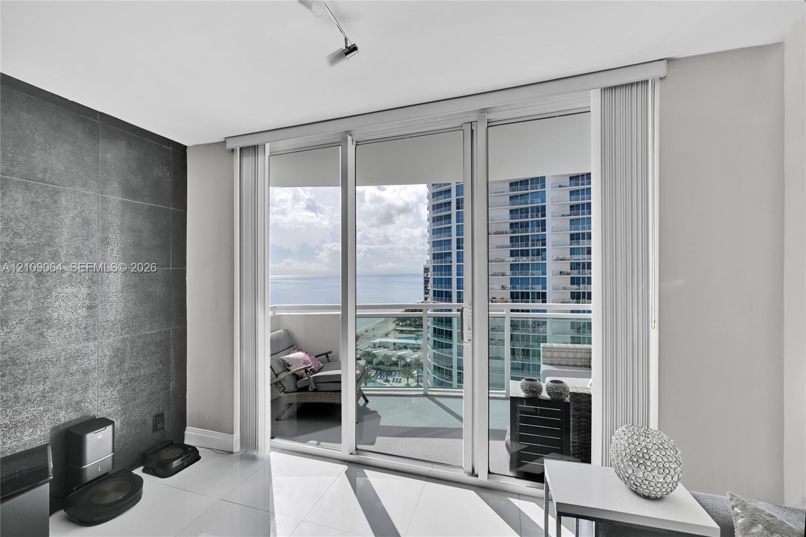 Open-concept interior featuring large-format polished tile flooring, floor-to-ceiling glass paneling, and adjustable track lighting