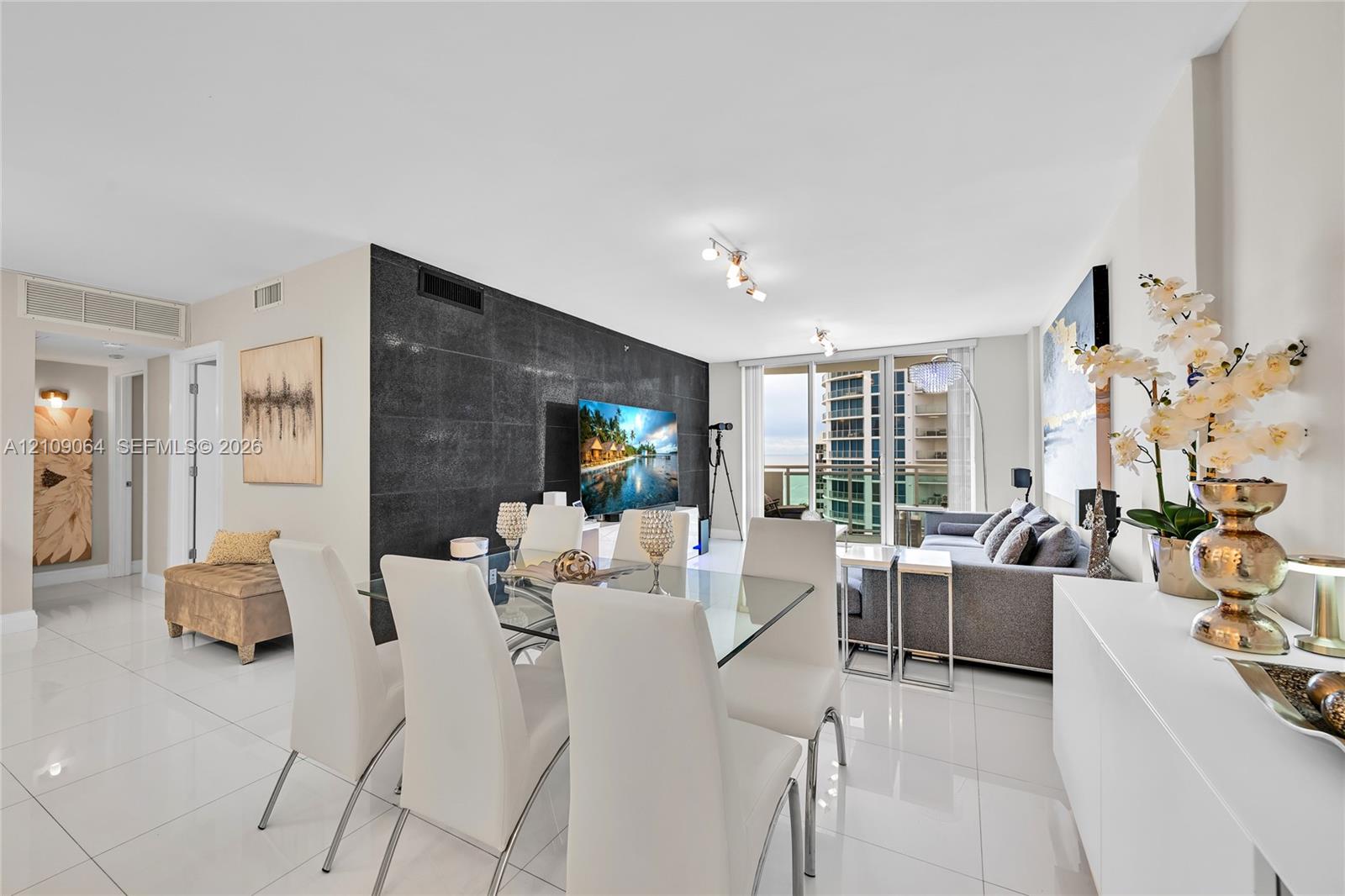 Large-format tile flooring, floor-to-ceiling glass sliding doors, private balcony, and multi-directional track lighting