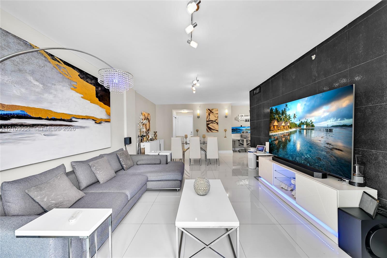 Open-concept interior featuring large-format tile flooring, a prominent black stone feature wall, dual wall-mounted light fixtures, and recessed ceiling lighting