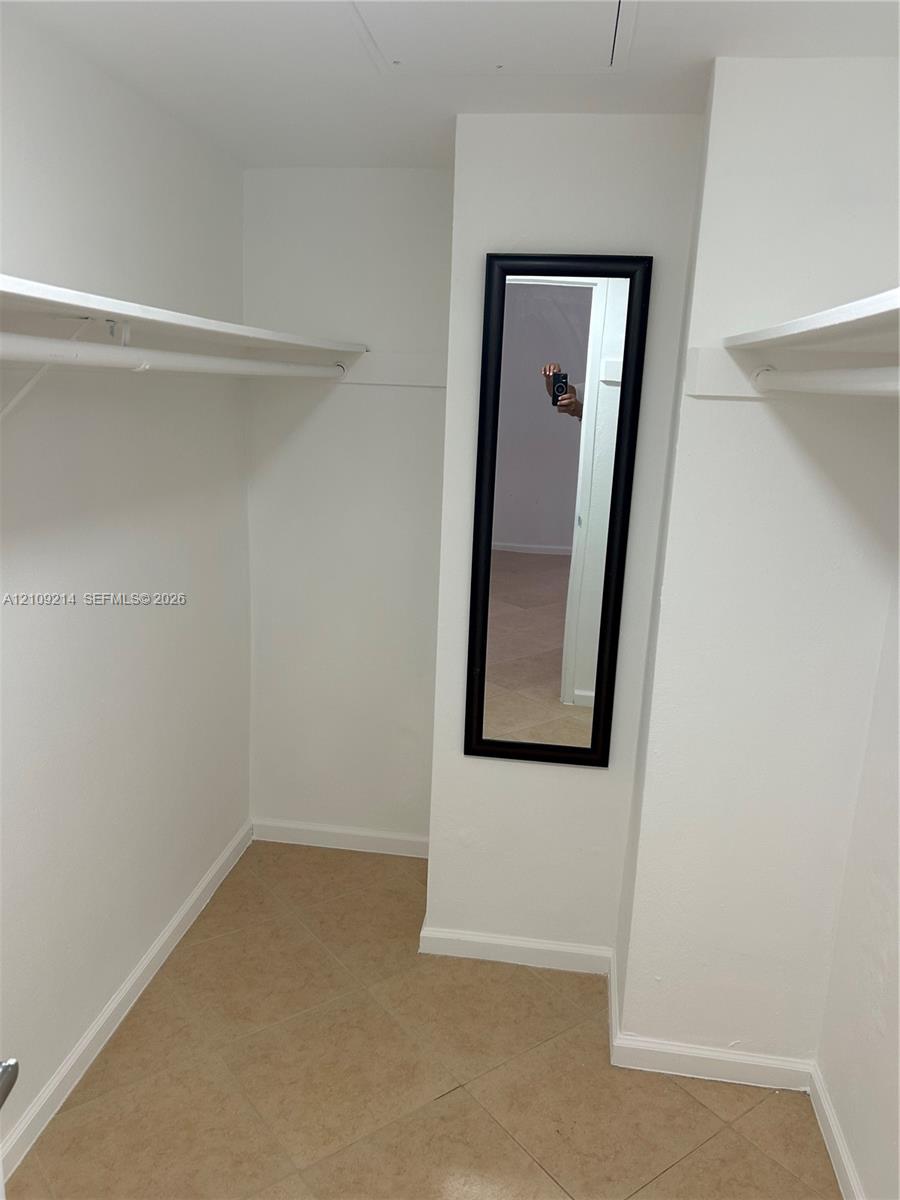 Walk-in storage space featuring ceramic tile flooring, built-in shelving
