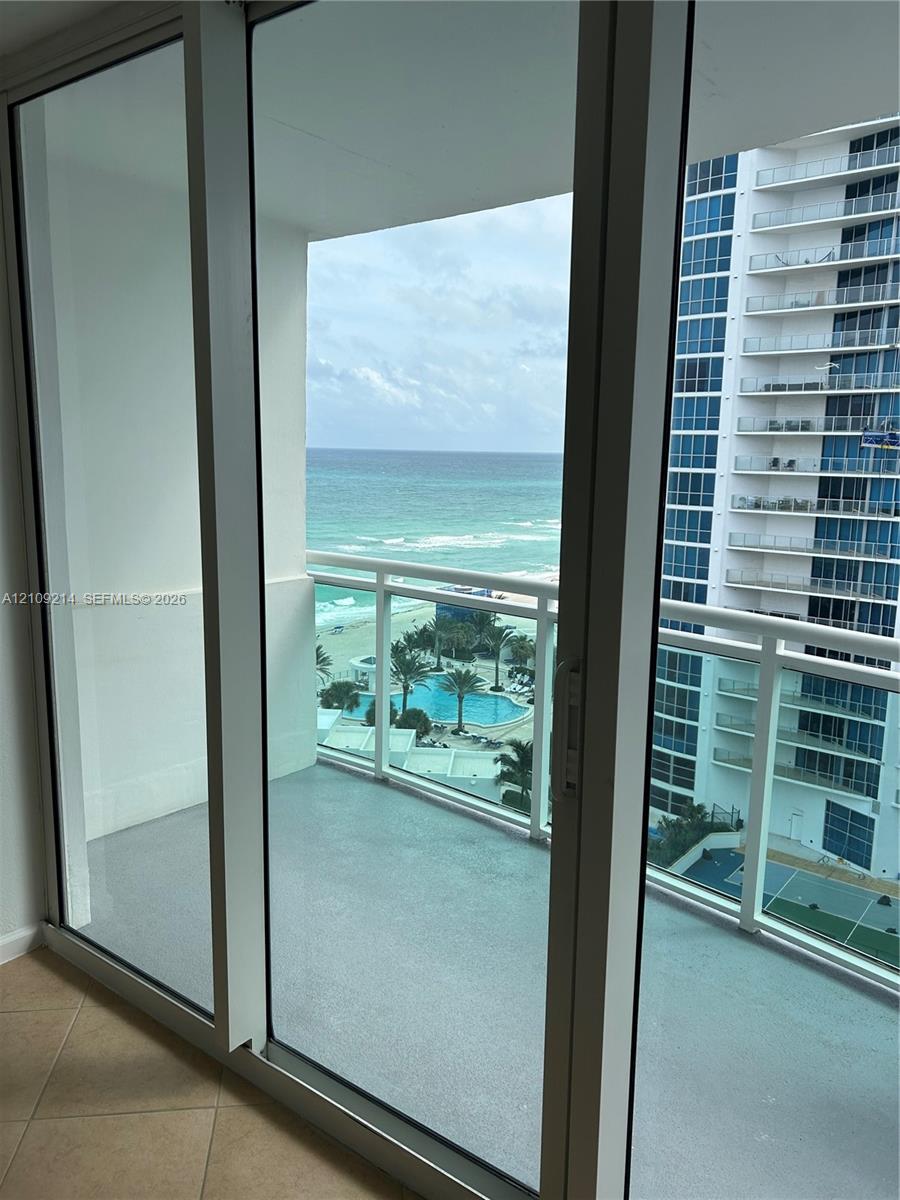 Floor-to-ceiling glass to a private balcony with horizontal railings, featuring direct water and coastal scenery