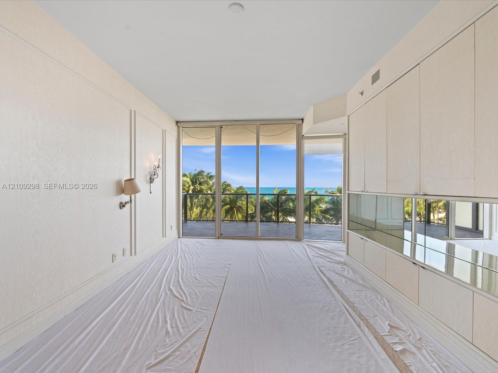 Full-height wall paneling, built-in cabinetry with mirrored backsplash, and floor-to-ceiling glass sliding doors opening to a covered balcony