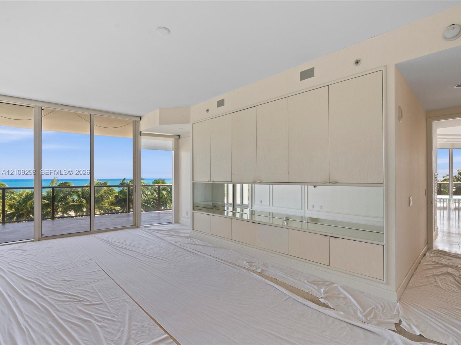 Floor-to-ceiling sliding glass doors, built-in floor-to-ceiling cabinetry with integrated mirror backsplash, and balcony with metal railing