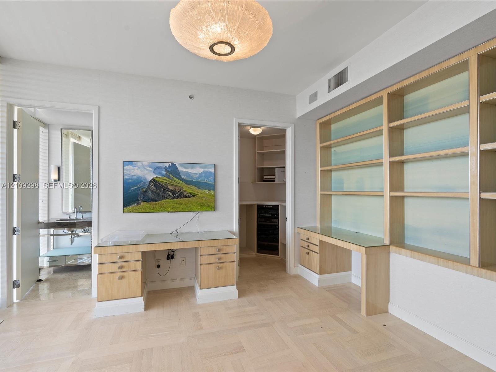 Custom light wood cabinetry with built-in desk surfaces, integrated shelving, flush-mount circular lighting, and parquet wood-finish flooring